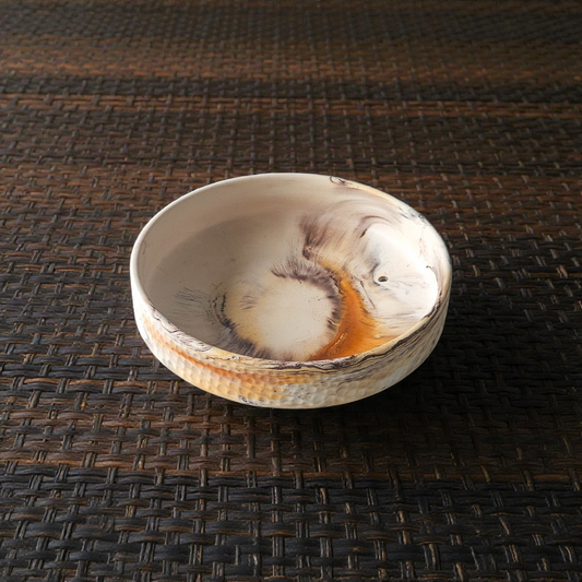 Ceramic bowl with natural patterns on a woven surface